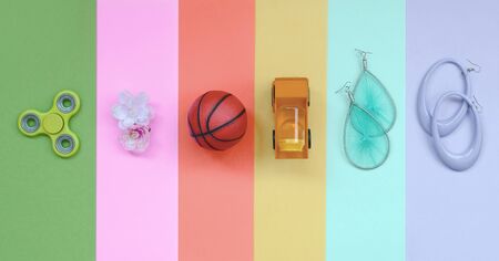 Trendy fashionable pastel composition with earrings, sunglasses, beverage can, basketball ball, toy truck, flower and spinner on background of pink, violet, green, orange, yellow and blue colors.の写真素材