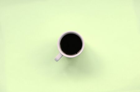 Small white coffee cup on texture background of fashion pastel lime color paper in minimal concept.の写真素材