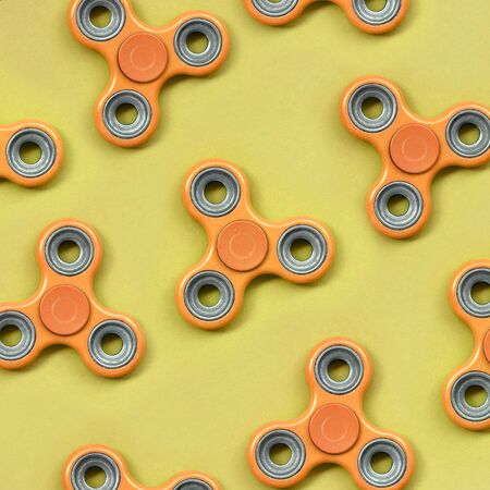 Many orange fidget spinners lies on texture background of fashion pastel orange color paper in minimal concept.の写真素材