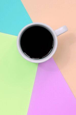 Small white coffee cup on texture background of fashion pastel pink, blue, coral and lime colors paper in minimal concept.の写真素材