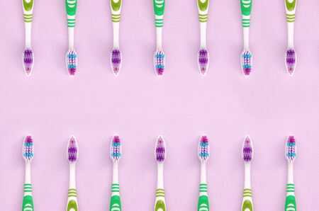 A lot of toothbrushes lie on a pastel pink background. Top view, flat lay. Minimal concept.の写真素材