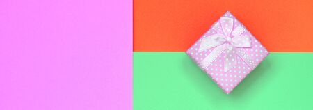 Small pink gift box lie on texture background of fashion pastel turquoise, red and pink colors paper in minimal concept.の写真素材