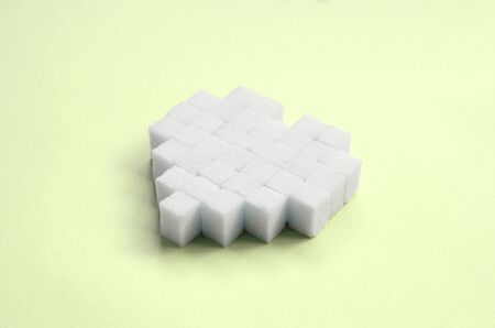A heart made of sugar cubes lies on a trendy pastel lime background.