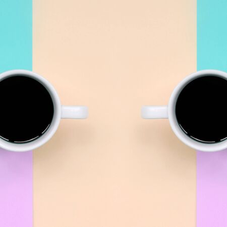 Two small white coffee cups on texture background of fashion pastel pink, blue, coral and lime colors paper in minimal concept.の写真素材