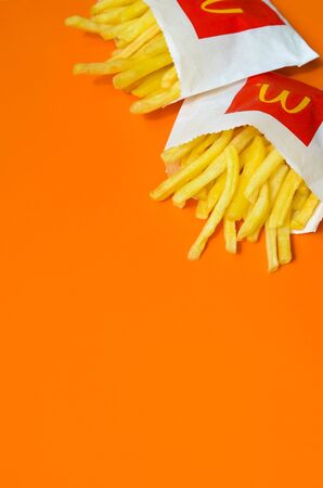 KHARKIV, UKRAINE - AUGUST 1, 2019: McDonald's French fries in small paperbag on bright orange...