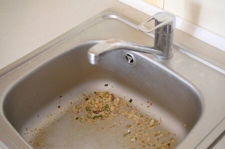 Close up on dirty clogging kitchen sink drain. Blur and selective focus of sink hole clogging up with food particlesの写真素材