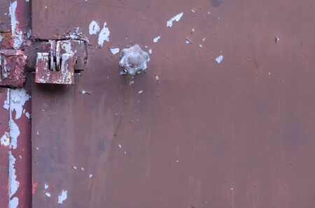 Closed metal lock garage door security protection padlock. Old brown gates with weathered peeling...