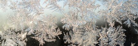 Snowflakes frost rime macro on window glass pane. Colorful ice on the window surface, natural...