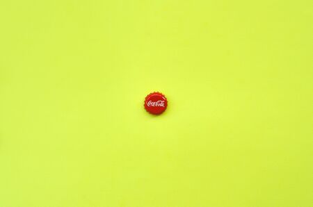 KHARKOV, UKRAINE - SEPTEMBER 8, 2019: Single red bottle lid with Coca Cola logo on yellow...