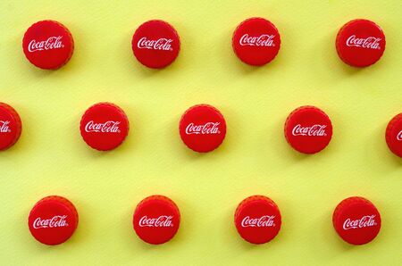 KHARKOV, UKRAINE - SEPTEMBER 8, 2019: Many red caps with coca cola logo on yellow background. The...
