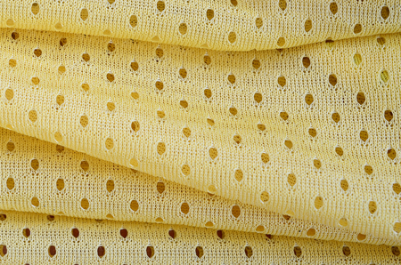 Yellow mesh sport wear fabric textile pattern background. Yellow color football jersey clothing fabric texture sports wear. Breathable porous poriferous material air ventilation with small holesのeditorial素材