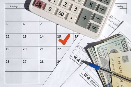 W-2 Wage and Tax statement blank with credit card on dollar bills, calculator and pen on calendar...