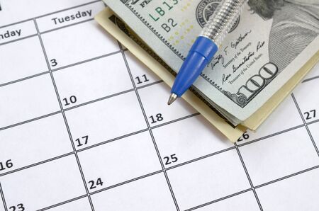 Pen and many hundred US dollar bills on calendar page close up. Business and financial planning concept. Accountant workの写真素材