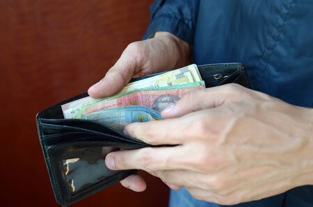 Close up male hands opened the wallet or purse with ukrainian money currency hryvnia. Salary in...