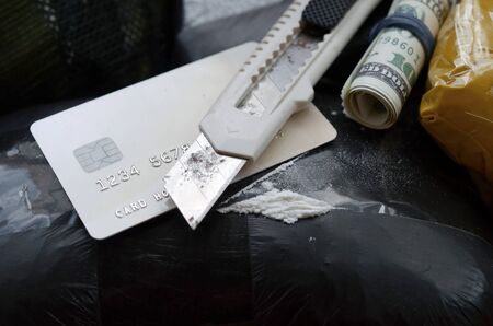 Spoon full of heroin and paper knife lies on drug packs and credit card with dollars roll. Concept of drug trafficking and dealing in United States territory. Narcotic dangerous businessの写真素材