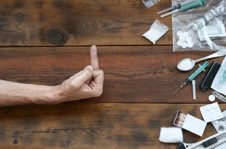 Male hand show FUCK sign to all of narcotic stuff definitions. Many drug pills and powder on wooden table. Fighting with drug abuse and dealingの写真素材