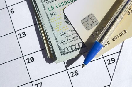 Pen and credit card on many hundred US dollar bills on calendar page close up. Business and...