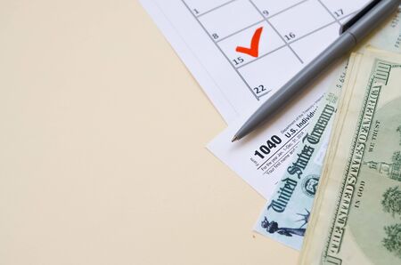 1040 Individual Income tax return form with Refund Check and hundred dollar bills on calendar with...