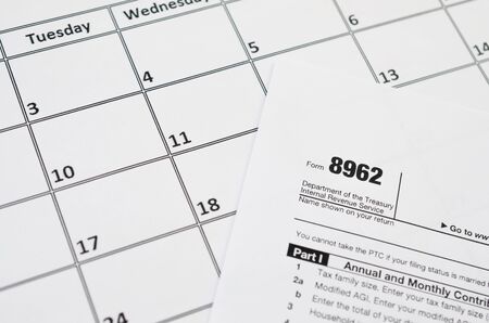 IRS Form 8962 Premium tax cerdit PTC blank lies on empty calendar page. Tax period concept. Copy...