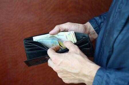 Close up male hands opened the wallet or purse with ukrainian money currency hryvnia. Salary in...