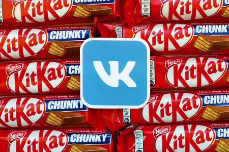 KHARKOV, UKRAINE - OCTOBER 17, 2019: Vkontakte paper logo on many Kit Kat chocolate covered wafer bars in red wrapping. Advertising chocolate product in Vkontakte social network and world wide webのeditorial素材