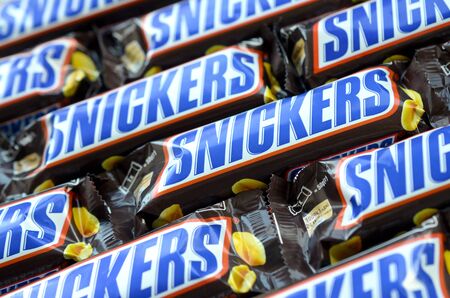 KHARKOV, UKRAINE - OCTOBER 2, 2019: Many Snickers chocolate bars stacked close up. Snickers bars are produced by Mars Incorporated. Snickers was created by Franklin Clarence Mars in 1930のeditorial素材