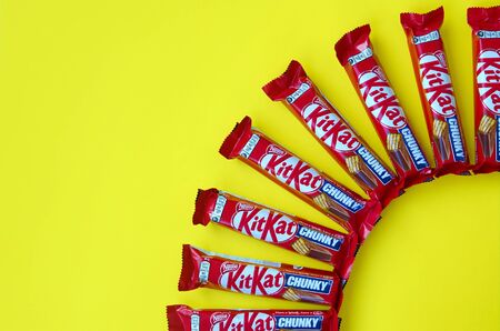 KHARKOV, UKRAINE - OCTOBER 17, 2019: Kit Kat chocolate bars in red wrapping lies on yellow background. Kit kat created by Rowntree's of York in United Kingdom and is now produced globally by Nestleのeditorial素材