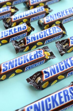 KHARKOV, UKRAINE - OCTOBER 2, 2019: Many Snickers chocolate bars lies on pastel blue paper. Snickers bars are produced by Mars Incorporated. Snickers was created by Franklin Clarence Mars in 1930のeditorial素材