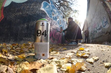 KHARKOV, UKRAINE - OCTOBER 19, 2019: Montana mtn 94 used spray can for graffiti painting outdoors in autumn leafs and artist in painting process on backgroundのeditorial素材