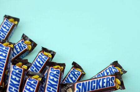 KHARKOV, UKRAINE - OCTOBER 2, 2019: Many Snickers chocolate bars lies on pastel blue paper. Snickers...