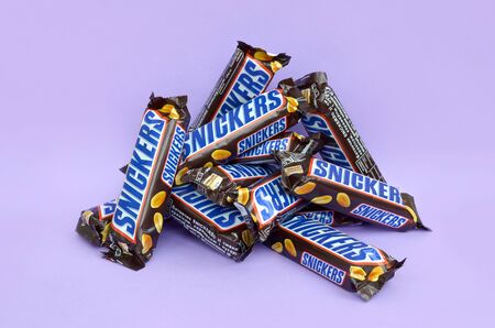 KHARKOV, UKRAINE - OCTOBER 2, 2019: Many Snickers chocolate bars lies on pastel lilac paper. Snickers bars are produced by Mars Incorporated. Snickers was created by Franklin Clarence Mars in 1930のeditorial素材