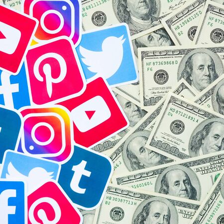 KHARKOV, UKRAINE - OCTOBER 3, 2019: Many hundred dollars bills with printed logo of social networks....