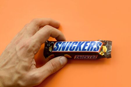 KHARKOV, UKRAINE - OCTOBER 2, 2019: Hand holding a Snickers chocolate bar. Snickers bars are...