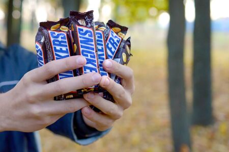 KHARKOV, UKRAINE - OCTOBER 8, 2019: A young caucasian man shows many Snickers chocolate bars in...