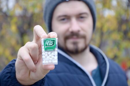 KHARKOV, UKRAINE - OCTOBER 26, 2019: Young man shows new Tic tac hard mints package in autumn park....