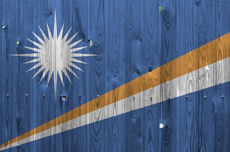 Marshall Islands flag depicted in bright paint colors on old wooden wall close up. Textured banner on rough backgroundの写真素材