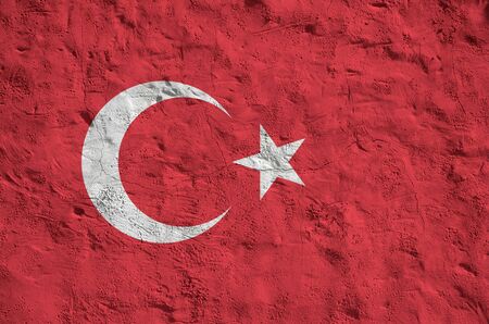 Turkey flag depicted in bright paint colors on old relief plastering wall close up. Textured banner on rough backgroundの写真素材