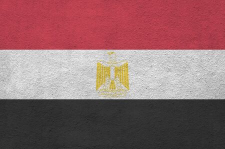 Egypt flag depicted in bright paint colors on old relief plastering wall close up. Textured banner on rough backgroundの写真素材