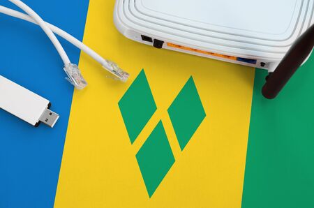 Saint Vincent and the Grenadines flag depicted on table with internet rj45 cable, wireless usb wi-fi...