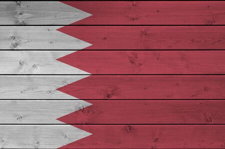 Bahrain flag depicted in bright paint colors on old wooden wall close up. Textured banner on rough...