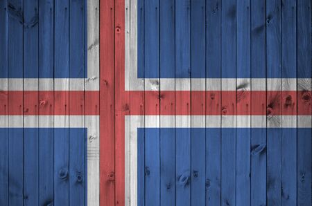 Iceland flag depicted in bright paint colors on old wooden wall close up. Textured banner on rough backgroundの写真素材
