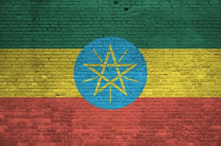 Ethiopia flag depicted in paint colors on old brick wall close up. Textured banner on big brick wall masonry background