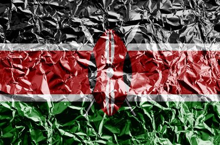 Kenya flag depicted in paint colors on shiny crumpled aluminium foil close up. Textured banner on rough backgroundの写真素材