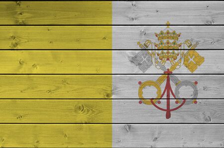 Vatican City State flag depicted in bright paint colors on old wooden wall close up. Textured banner on rough backgroundの写真素材
