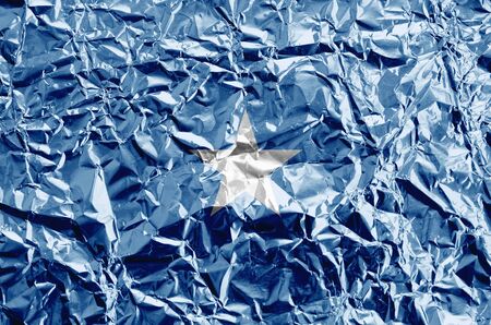 Somalia flag depicted in paint colors on shiny crumpled aluminium foil close up. Textured banner on rough backgroundの写真素材