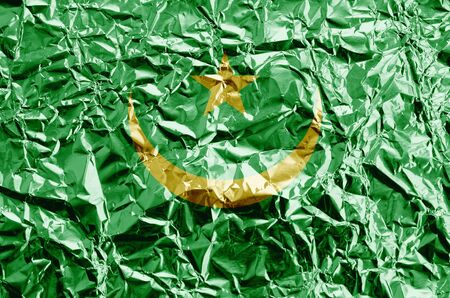 Mauritania flag depicted in paint colors on shiny crumpled aluminium foil close up. Textured banner on rough backgroundの写真素材
