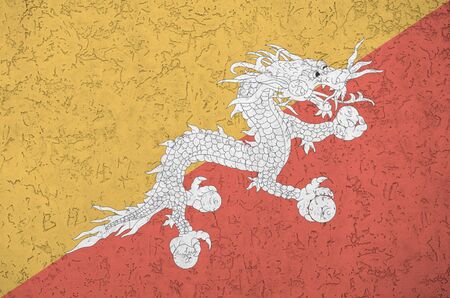 Bhutan flag depicted in bright paint colors on old relief plastering wall close up. Textured banner on rough backgroundの写真素材