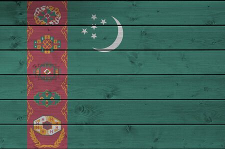 Turkmenistan flag depicted in bright paint colors on old wooden wall close up. Textured banner on rough backgroundの写真素材