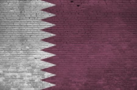 Qatar flag depicted in paint colors on old brick wall close up. Textured banner on big brick wall masonry backgroundの写真素材