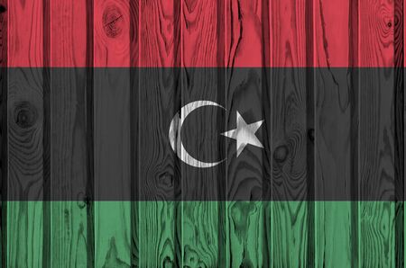 Libya flag depicted in bright paint colors on old wooden wall close up. Textured banner on rough backgroundの写真素材